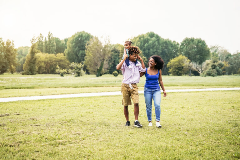 Happy African family walking together in public park - Mother father and baby daughter having fun spending time together outdoor - Happiness, love and parenthood concept